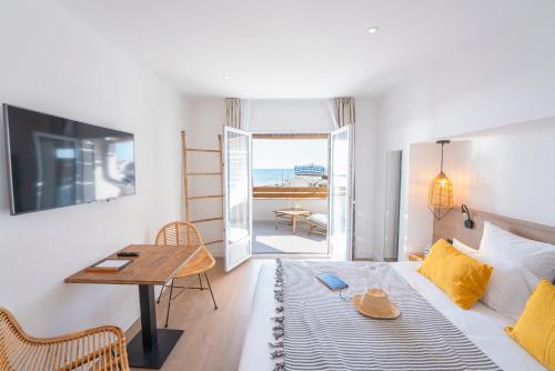 a room with a bed and a table and a desk at Hôtel Casa Marina in Saintes-Maries-de-la-Mer