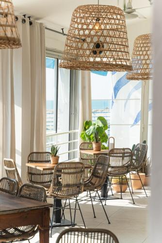 a dining room with chairs and tables and windows at Hôtel Casa Marina in Saintes-Maries-de-la-Mer