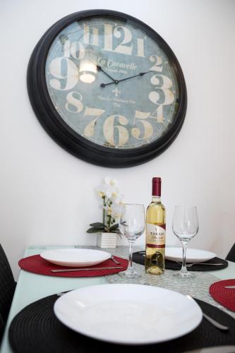 a table with glasses and a clock on the wall at Kossuth Apartmanház in Tata
