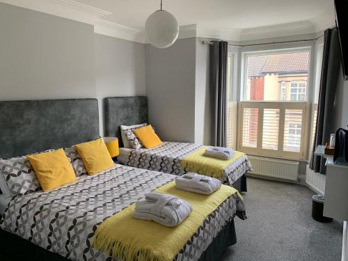 two beds in a room with yellow pillows on them at Armada Guesthouse in Redcar