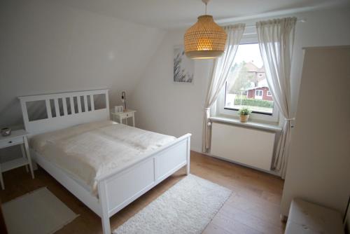 a bedroom with a white bed and a window at Ferienwohnung HeideZeit Soltau - Neu mit Spielturm in Soltau