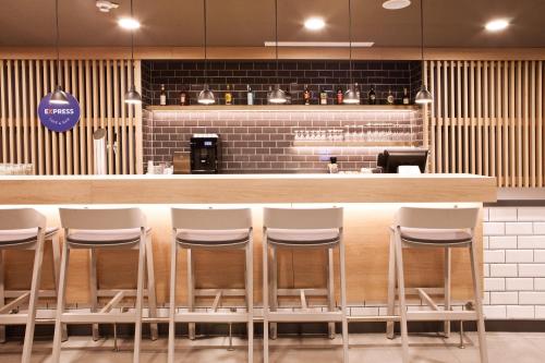 a bar with white stools in a restaurant at Holiday Inn Express Munich - Olching by IHG in Olching