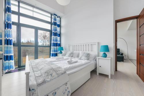 a white bedroom with a bed and a large window at Apartamenty Sun & Snow Dune A in Mielno