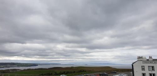 a view of a river and a building on a hill at Causeway Hotel in Bushmills
