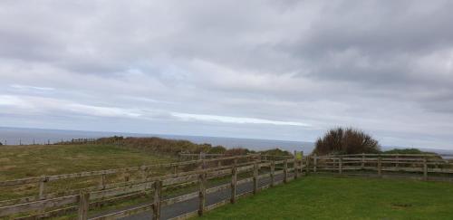 a fence on top of a hill with the ocean at Causeway Hotel in Bushmills