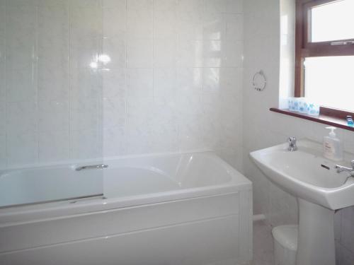 Baño blanco con bañera y lavamanos en Clydagh Lodge, en Castlebar