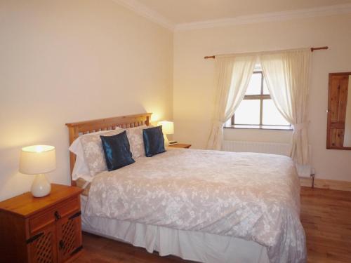 a bedroom with a bed with blue pillows and a window at Clydagh Lodge in Castlebar