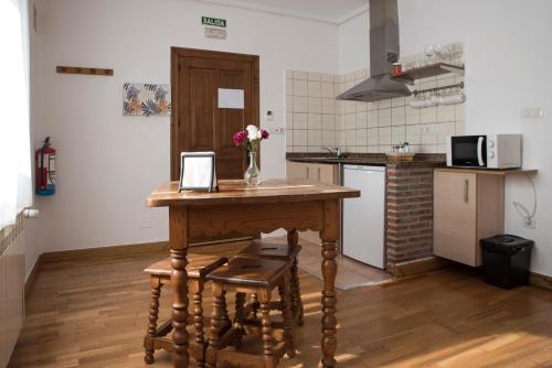 a kitchen with a table with a vase of flowers on it at Apartamentos Alegría in Santillana del Mar