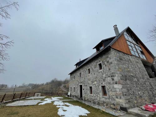 an old stone building in a field with snow at Molla Guest House in Theth