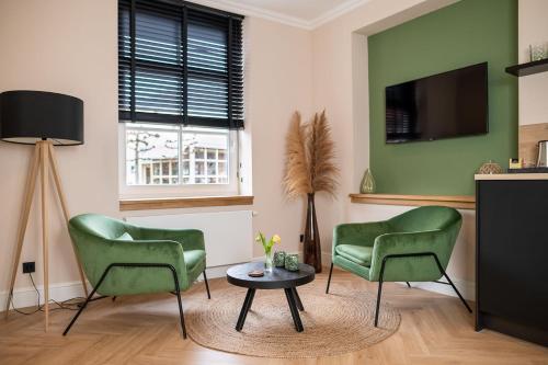 een woonkamer met 2 groene stoelen en een tafel bij Bed en Baguette in Burgh Haamstede