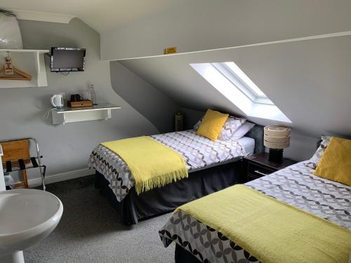 a bedroom with two beds and a sink and a window at Armada Guesthouse in Redcar