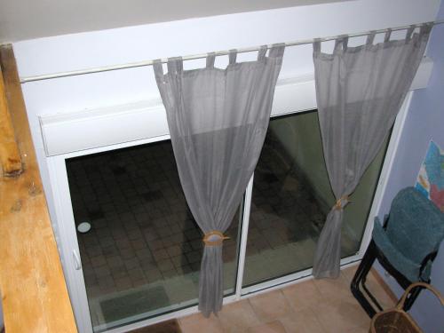 a window with curtains in a room with a chair at La Bergerie du festel in Saint-Riquier