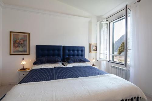 una camera da letto con un grande letto con testiera blu e finestra di Come Eravamo a Monterosso al Mare