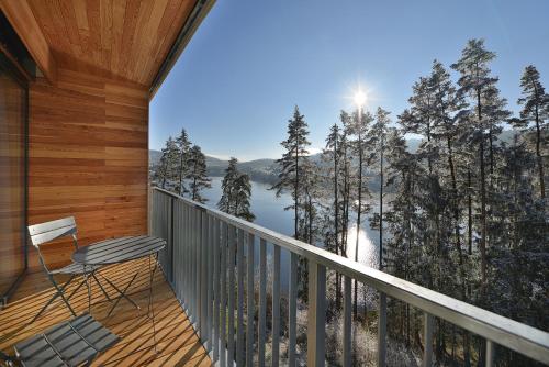 a chair on a balcony with a view of a lake at Element Lakeside Apartments in Lipno nad Vltavou