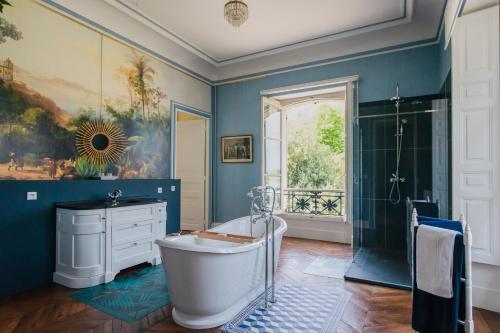 a bathroom with blue walls and a tub and a shower at Château de Cesny-aux-Vignes in Cesny-aux-Vignes