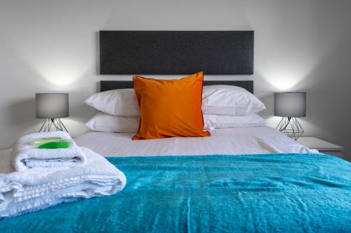 a bedroom with a large bed with an orange pillow at Parkhill Luxury Serviced Apartments - Hilton Campus in Aberdeen