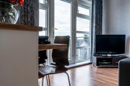 a living room with a desk and a television at Parkhill Luxury Serviced Apartments - Hilton Campus in Aberdeen