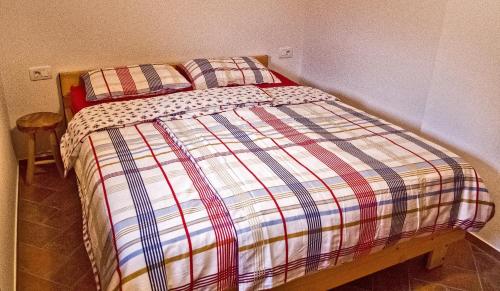 łóżko z kołdrą w paskach w sypialni w obiekcie Vineyard cottage Podržaj w mieście Otočec