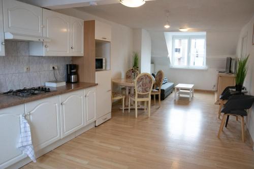 a kitchen and living room with white cabinets and a table at West Side Roses appartement in Ostend