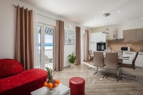 sala de estar con sofá rojo y cocina en FBA Family Beach Apartments, en Omiš