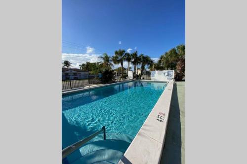 a swimming pool with blue water and palm trees at !!Coral Sands 1 Bedroom Stunner!! in West Palm Beach