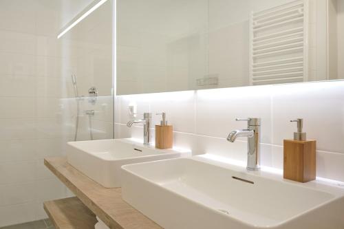 a white bathroom with a sink and a mirror at die Tauplitz Lodges - Alm Lodge A3 by AA Holiday Homes in Tauplitz