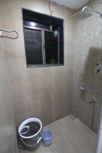 a bathroom with a window and a bucket at Green Arc Homestay in Malvan