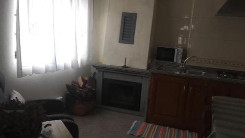 a living room with a fireplace and a microwave at Casa do Outeirinho in Sabugueiro