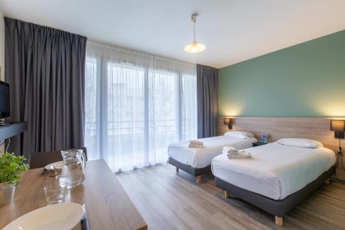 ein Hotelzimmer mit 2 Betten und einem Tisch in der Unterkunft Zenitude Hôtel-Résidences Le Mans Novaxis in Le Mans