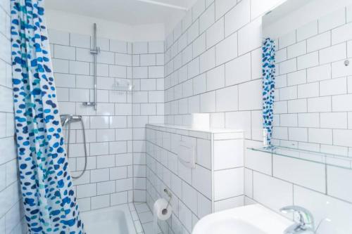 a white tiled bathroom with a shower and a toilet at Apartment 120 qm -3 Schlafzimmer-2 Bäder- für 8 Gäste in Düsseldorf