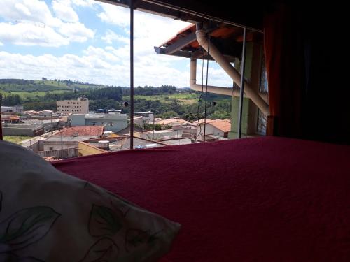 a bedroom with a purple bed and a view of a city at HOSTEL DO PAPAI 2 in Lavras