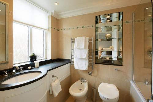 a bathroom with a sink and a toilet and a shower at Cheval Knightsbridge in London