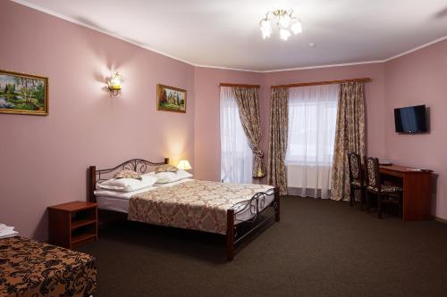Schlafzimmer mit einem Bett, einem Schreibtisch und einem TV in der Unterkunft Panska Rovin Hotel in Mohnate