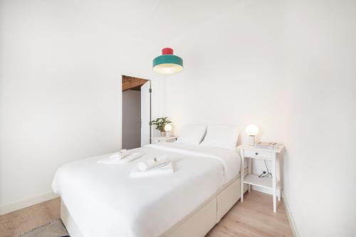 een witte slaapkamer met een wit bed en een tafel bij Comfy Apartment by Olala Homes in Cascais
