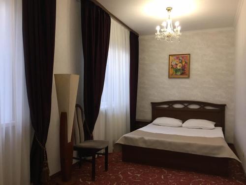a bedroom with a bed and a chair and a chandelier at Hotel-Restaurant Lyube Plus in Khmelʼnytsʼkyy
