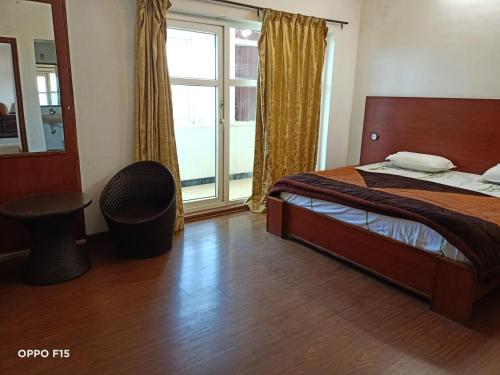 a bedroom with a bed and a large window at Apple Breeze Resort in Kotagiri