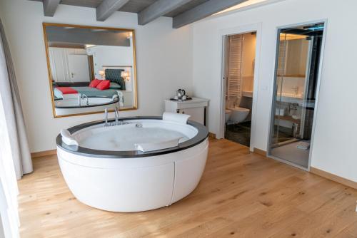 - dużą białą wannę w pokoju z lustrem w obiekcie Cristallo Wellness Hotel w mieście Aprica