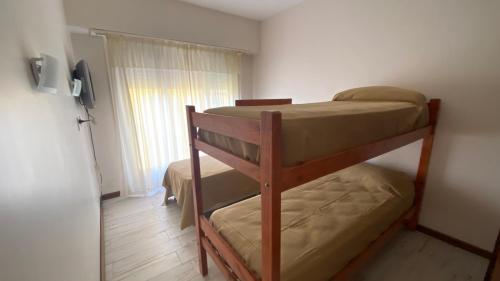 Departamentos Premium Miramar في ميرامار: سريرين بطابقين في غرفة صغيرة مع نافذة