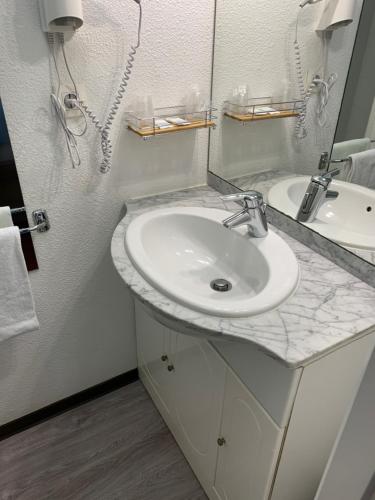 a bathroom with a sink and a mirror at L'Auberge Everhotel de Tarbes-Ibos in Tarbes