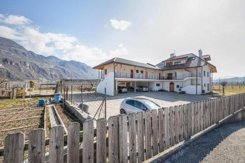 a house with a car parked in front of a fence at Ferienwohnung 2 Weger in Andrian