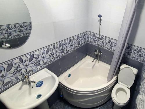 a bathroom with a tub and a toilet and a sink at Guest House Art Postindoz in Khiva