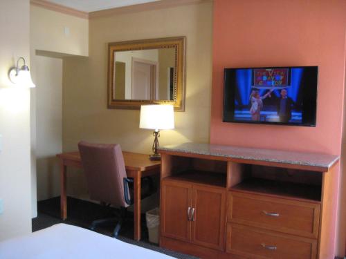 a hotel room with a desk and a tv on a wall at Americas Best Value Inn - Porterville in Porterville