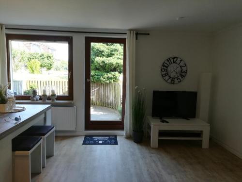 a living room with a television and a clock on the wall at 2 Zimmer Ferienwohnung Ostseetraum Haffkrug in Scharbeutz