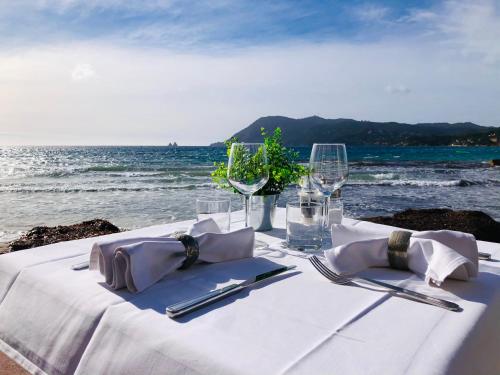 a white table with glasses and napkins on the beach at Le Cannier Hotel in La Seyne-sur-Mer