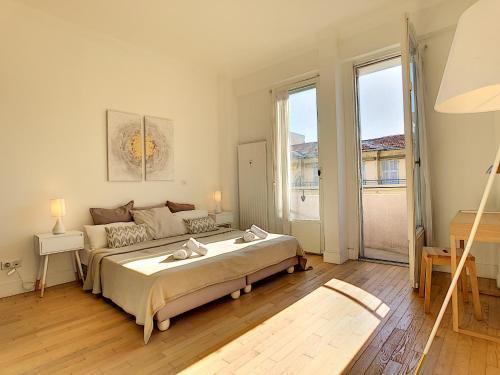 une chambre avec un grand lit et une grande fenêtre dans l'établissement Nestor&Jeeves - GLORIA BEACH - Very close sea - Prestigious building, à Nice