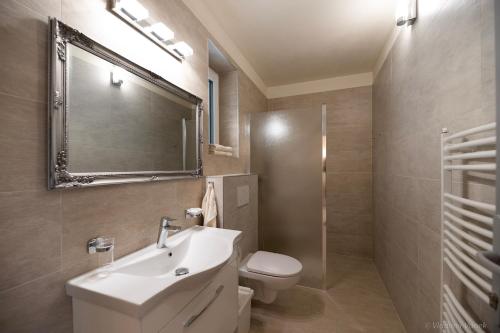 y baño con lavabo, aseo y espejo. en Apartmány I - KAfe Bojnice, en Bojnice