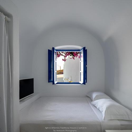 a bedroom with a bed and a window at Aghios Artemios Traditional Houses in Imerovigli