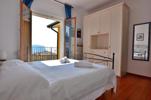 a bedroom with a white bed and a large window at Orange Apartment In Marciaga di Costermano in Costermano