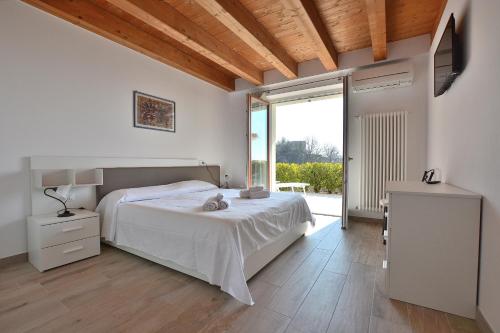 biała sypialnia z łóżkiem i dużym oknem w obiekcie Red Apartment in Marciaga di Costermano w mieście Costermano
