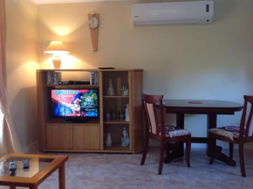 sala de estar con TV, mesa y sillas en The Cook Cottage, en Canberra